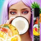 A person with purple hair holds a halved coconut in front of their mouth. The foreground showcases an assortment of tropical fruits and a bottle labeled "Wet 'Tropical Explosion' Warming Lubricant 🍍," which claims to function as an oral, massage, and warming lubricant aid.